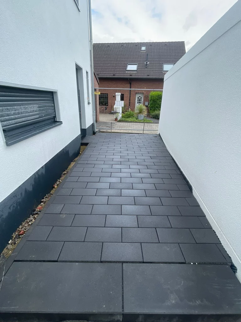 Gepflasterter Weg zwischen Haus und Grundstücksmauer in Mönchengladbach